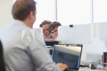 Playful business people watching colleague at laptop