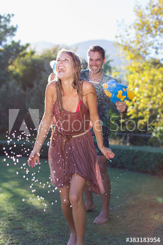 Playful couple with squirt gun in backyard