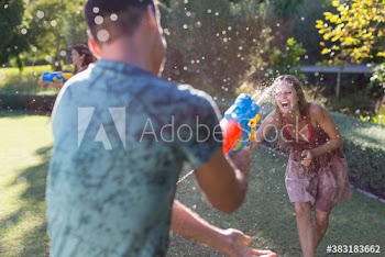 Playful couple with squirt guns in backyard