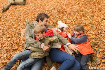 Playful family laying in autumn leaves