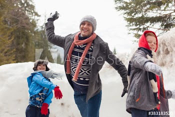 Playful father and sons throwing snowballs