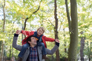 Playful father carrying son on shoulders in park