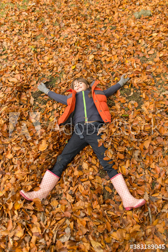 Playful girl laying in autumn leaves