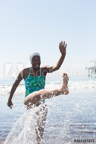 Playful woman splashing in sunny ocean