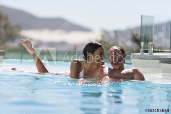 Playful young couple in sunny swimming pool