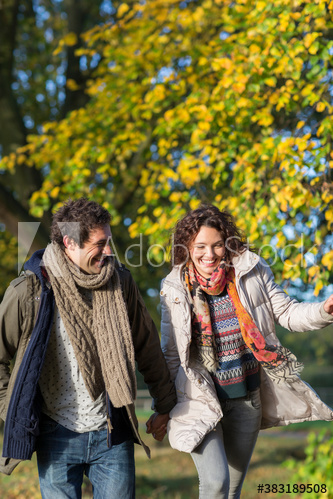 Playful young couple running in autumn park