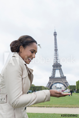 Playful young woman pretending to hold Eiffel Tower in palm, Paris