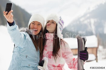 Playful young women friends taking selfie in snow
