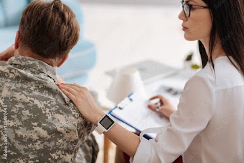 Pleasant nice therapist putting her hand on the soldiers shoulder