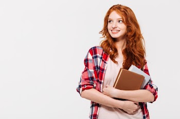 Pleased ginger woman in shirt holding books and looking away Free Photo