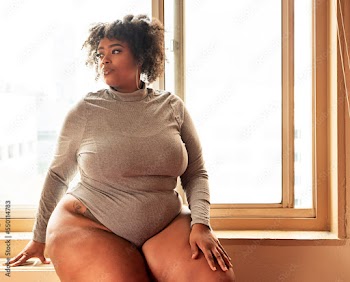 Plus size Black Woman sitting in front of a window