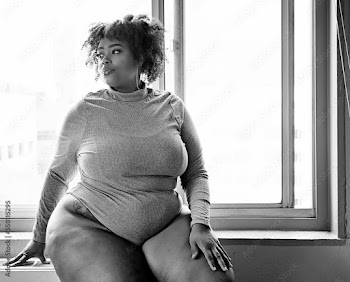 Plus size Black Woman sitting in front of a window