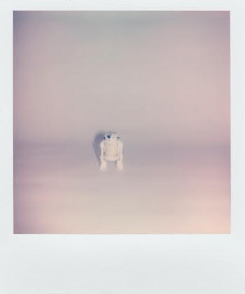 Polaroid Photo Of A Small Robot Toy In White Background  