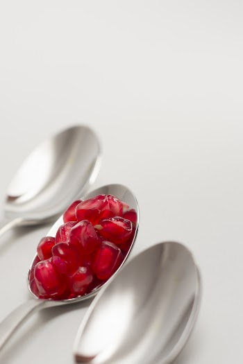 Pomegranate Seed on Spoon Between Empty Spoons