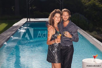 Portrait attractive couple drinking cocktails at poolside