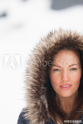 Portrait beautiful young woman in fur hood in snow
