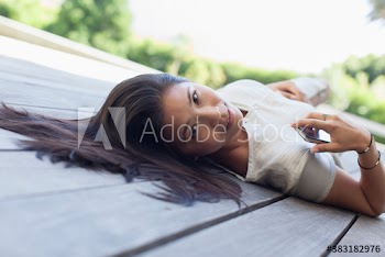 Portrait beautiful young woman laying on deck with smart phone