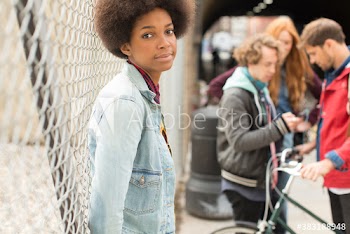 Portrait beautiful young woman with afro at chainlink fence