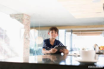 Portrait boy using digital tablet at kitchen counter