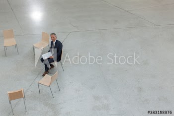 Portrait businessman waiting in circle of chairs