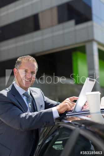 Portrait businessman with digital tablet at car in parking lot