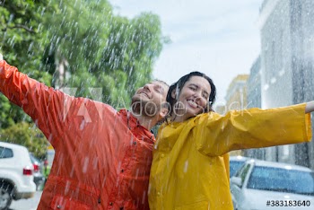 Portrait carefree couple hugging on rainy street