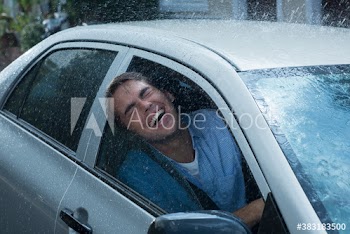 Portrait carefree man with head outside car window in rain
