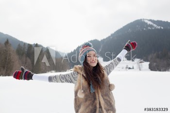 Portrait carefree young woman with arms outstretched in snowy field