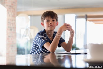 Portrait confident boy with digital tablet at kitchen counter
