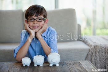 Portrait confident boy with piggybanks