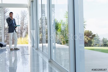 Portrait confident businessman standing at window in modern house