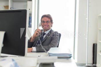 Portrait confident businessman talking on telephone at computer