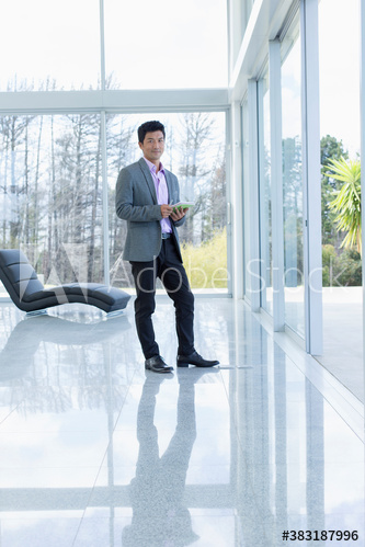 Portrait confident businessman using digital tablet in modern house