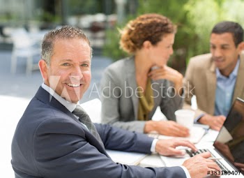 Portrait confident businessman using laptop at outdoor cafe