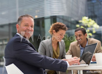 Portrait confident businessman using laptop at outdoor cafe