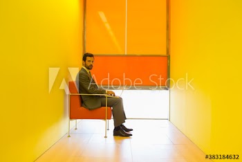 Portrait confident businessman using laptop in modern yellow office
