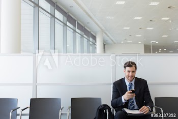 Portrait confident businessman using smart phone in office lobby