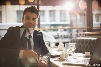 Portrait confident businessman with laptop working in restaurant