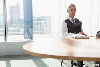 Portrait confident corporate businessman in sunny conference room