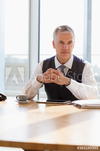 Portrait confident corporate businessman with digital tablet at table