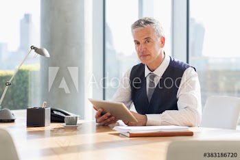 Portrait confident corporate businessman with digital tablet in sunny office