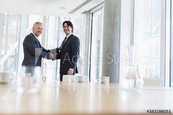 Portrait confident corporate businessmen shaking hands in conference room