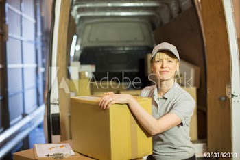 Portrait confident deliverywoman with box outside delivery van