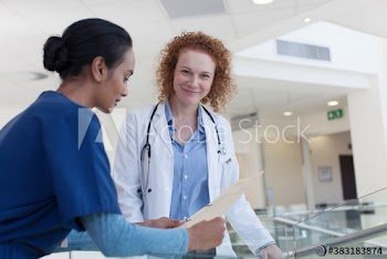 Portrait confident female doctor consulting with nurse in hospital