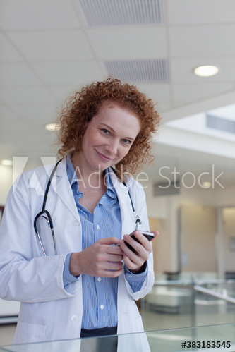 Portrait confident female doctor with smart phone in hospital