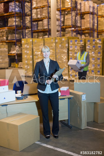Portrait confident female manager at desk in distribution warehouse