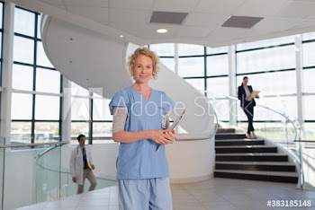 Portrait confident female nurse in modern hospital corridor