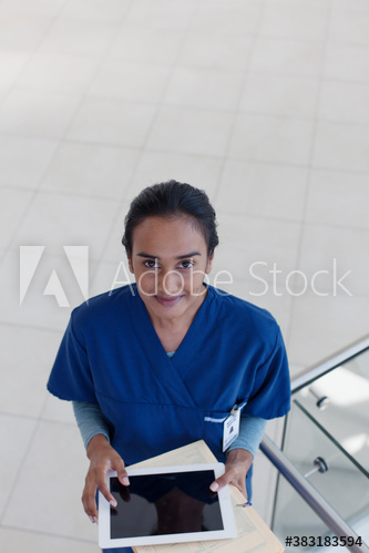 Portrait confident female nurse with digital tablet in hospital