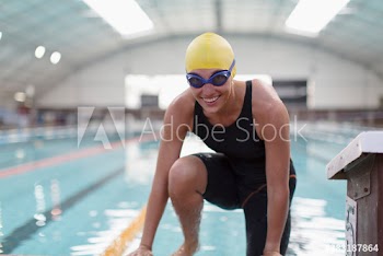 Portrait confident female swimmer at edge of swimming pool