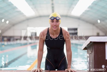 Portrait confident female swimmer at edge of swimming pool